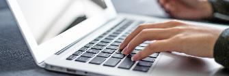 
Handen typen op een laptop gegevens in voor de online-boeking.