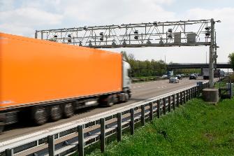 
Samochód ciężarowy mija mostek kontrolny na autostradzie